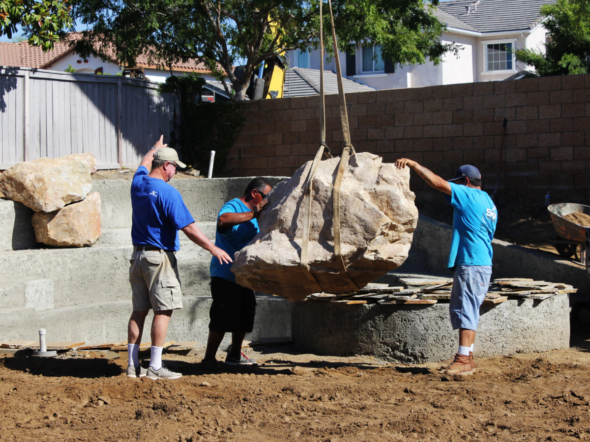 Crane placing boulder on landscape